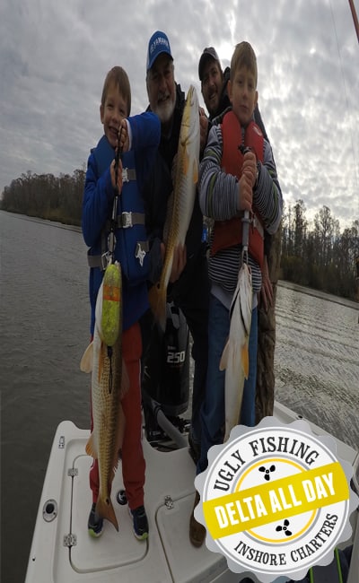 Two men and two boys holding redfish on a boat