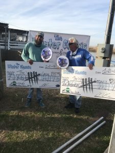 two fisherman holding big checks and plaques